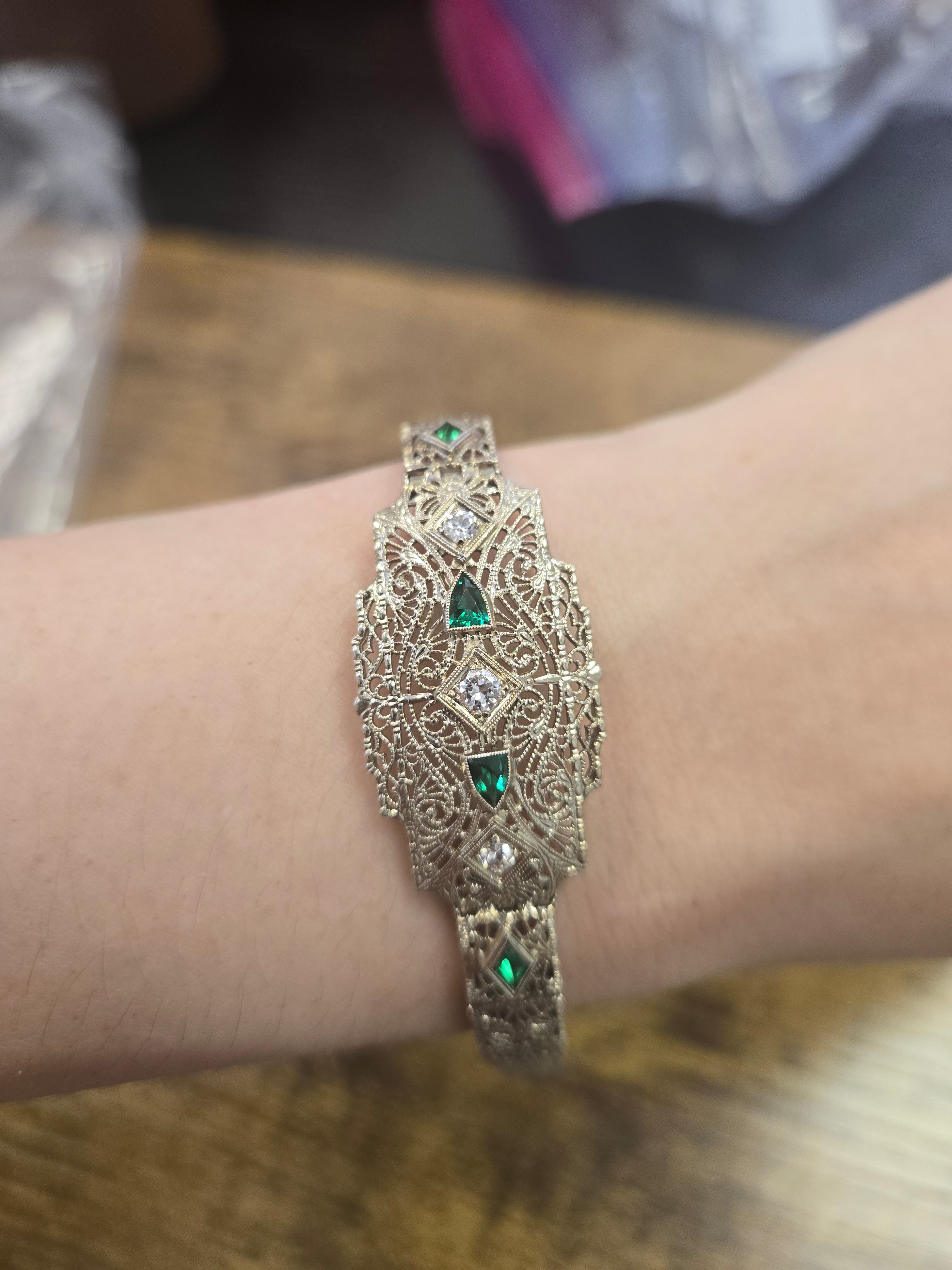 Art Deco 14K gold filigree diamond and emerald bracelet worn on wrist